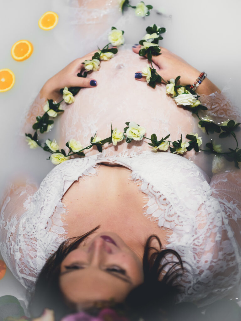 Femme enceinte dans bain de lait et fleurs